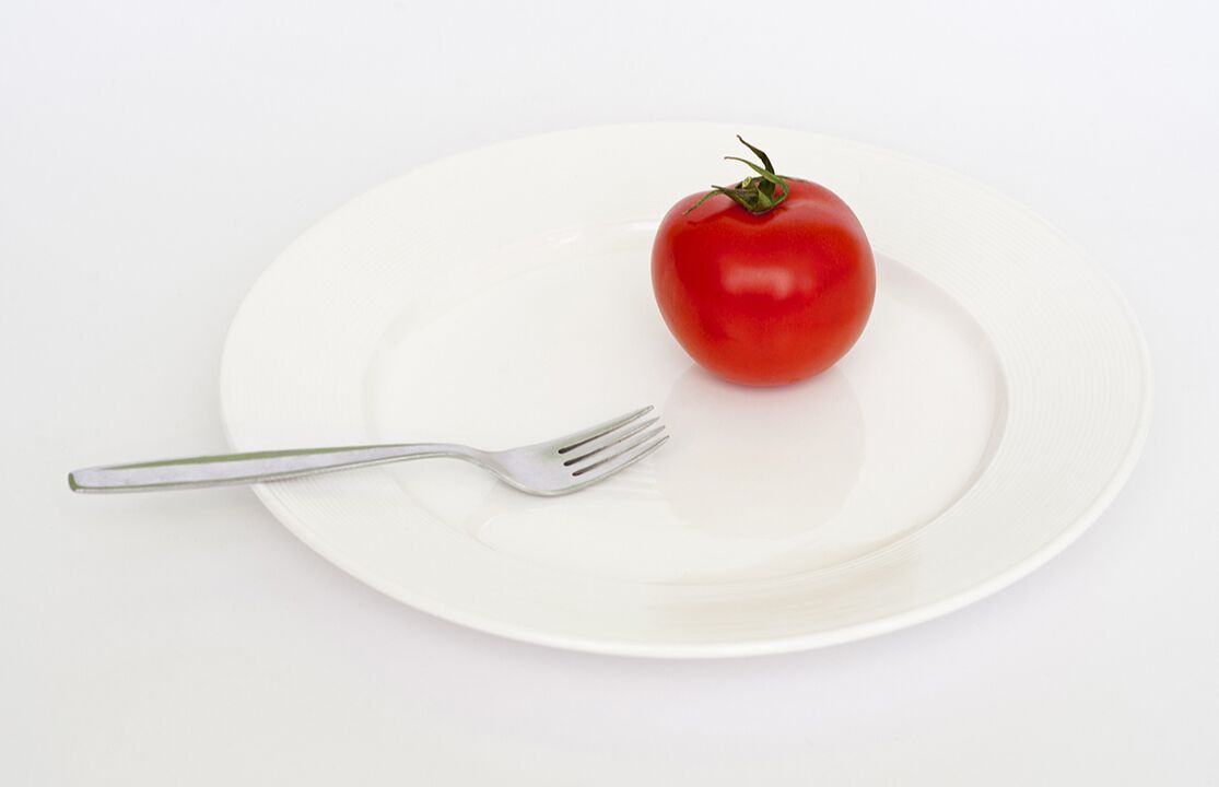 Tomate mit einer Gabel auf einem Teller